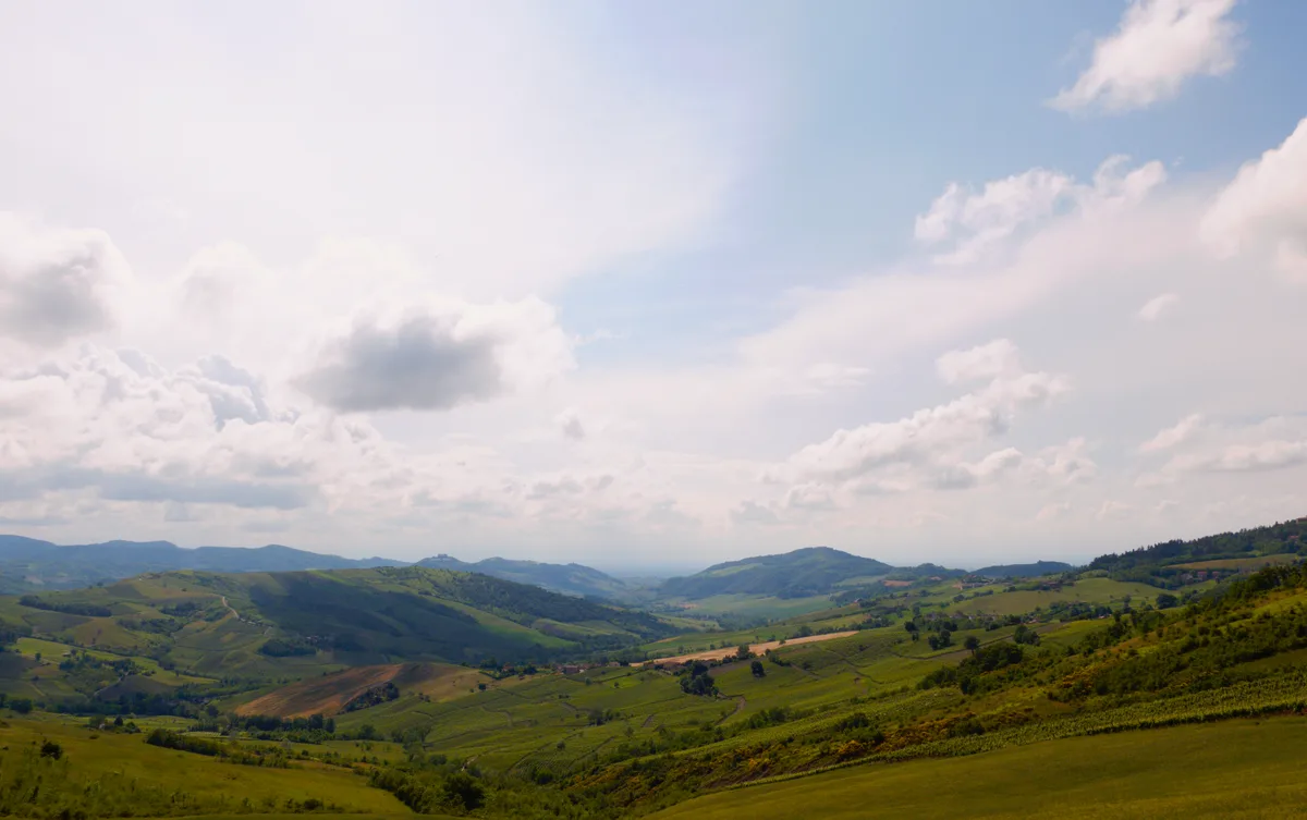 A green valley under billowing clouds, developed with deeper contrast, richer color, and a warmer light